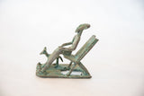 Side profile of the vintage copper man and dog, showing rich green patina and rustic texture.