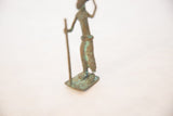 The oxidized copper base and hand-molded feet of the vintage walking figure.