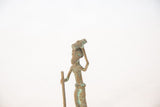 Close-up showing the stylized head and green oxidized patina of a vintage African figure.