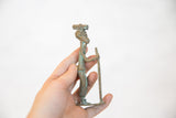 Vintage African copper figurine held in hand, showing its oxidized patina and scale.