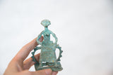 Vintage African copper figure with a green patina held in hand for scale.