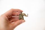 Vintage bronze elephant pendant with mesh detail, held to show its size.