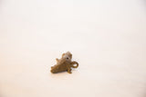 A vintage African bronze crocodile pendant's coiled tail and integrated hanging loop.