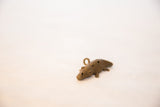 Angled view of a vintage bronze crocodile pendant highlighting its rustic, handmade details.