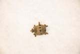 Vintage bronze turtle pendant showing its coiled wire shell and aged patina.