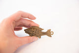 Large bronze wire fish pendant held in hand to illustrate its scale and texture.
