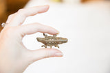 A vintage bronze crocodile pendant with a mesh body held for scale.