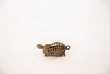 Handmade bronze turtle pendant in profile, detailing the mesh shell and vintage patina.