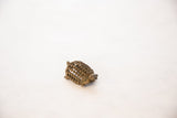 Angled view of the handmade bronze turtle pendant highlighting its mesh shell and aged patina.