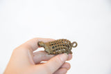 Vintage bronze turtle pendant held to show its scale, mesh shell, and detailed side profile.
