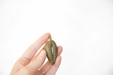 Vintage bronze pendant with aged patina and textured surface held to show scale.