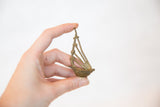 Vintage African bronze musical instrument held to show its small, handmade scale.