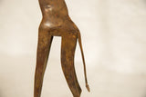The slender hind legs and tail of the copper giraffe with aged, textured patina.