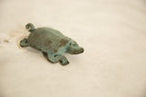 Close-up of vintage African copper turtle head with sculpted features and verdigris patina.