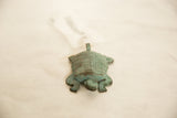 African Copper Turtle, showing its head, front legs, and grid-patterned shell with green patina.