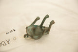 Vintage African oxidized copper frog from below, revealing textured green patina and handmade form.