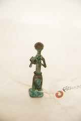 Rear profile of a vintage African copper farmer, showing its slender form and oxidized patina.