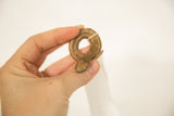 A hand holding the small vintage bronze snake, highlighting its coiled shape and handmade texture.