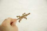 Hand holds a vintage African bronze crocodile figure with detailed scales and light patina.