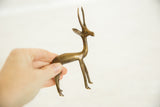 Hand holding the slender bronze body and legs of the vintage African gazelle.