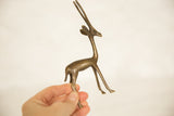 A hand holding the small, vintage African bronze gazelle sculpture.