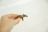 Small vintage African bronze hippopotamus figurine held in a hand, showing its textured finish.