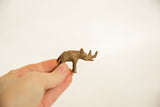 Small vintage African bronze rhinoceros sculpture held in hand to show its scale.