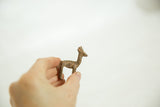 Hand holding a vintage African bronze antelope calf, highlighting its rustic texture and patina.