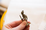 Small vintage African bronze soldier held in hand, displaying unique texture and aged patina.