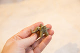 Handmade bronze elephant pendant with a mesh design and oxidized finish, held for scale.