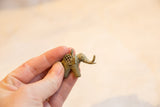 Vintage bronze elephant pendant held in hand to show its small scale and mesh design.