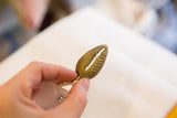 Textured surface and aged patina of a vintage African bronze bean pod pendant.