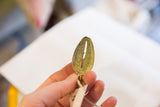 Vintage African bronze pendant held to show the textured green oxidized surface.