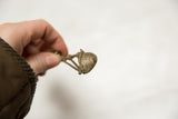 Aged bronze texture of a vintage African musical instrument pendant.