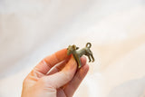 Vintage African ram pendant in profile, showing its rustic texture and curled tail.
