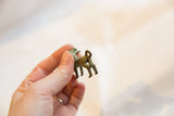 The back of the handmade bronze ram pendant, showing the looped tail and aged surface.
