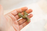 A vintage bronze rooster pendant with a textured, oxidized patina held in hand for scale.