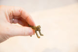 Vintage African bronze monkey pendant held to demonstrate its small, collectible scale.