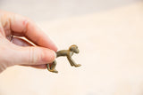 Vintage bronze monkey pendant held to demonstrate its small size and handmade texture.