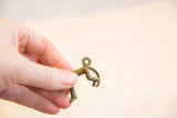 Small vintage African bronze monkey pendant held in hand to show its scale and form.