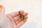 Vintage African bronze sitting monkey pendant held in a palm to show its small size.