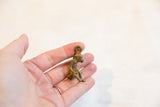 Vintage bronze monkey pendant held in a hand to show its small scale and handmade texture.