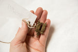 A small bronze turtle pendant held in hand to demonstrate its handmade texture and scale.
