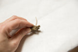 Vintage bronze turtle pendant held in hand to show its petite scale.