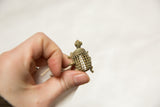 A small vintage African bronze turtle pendant held to show its size and mesh shell.