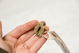 Vintage African oxidized bronze mesh design turtle pendant held in hand with tag.