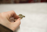 Vintage bronze turtle pendant held in hand, showing its small scale and criss-cross shell.