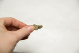 Vintage bronze turtle pendant held between fingers to demonstrate its small size.
