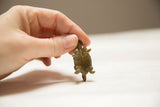 A view of the handmade bronze turtle pendant's textured underside and legs.