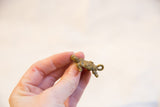 Side profile of the small bronze turtle pendant, showing its aged patina and spiral shell.